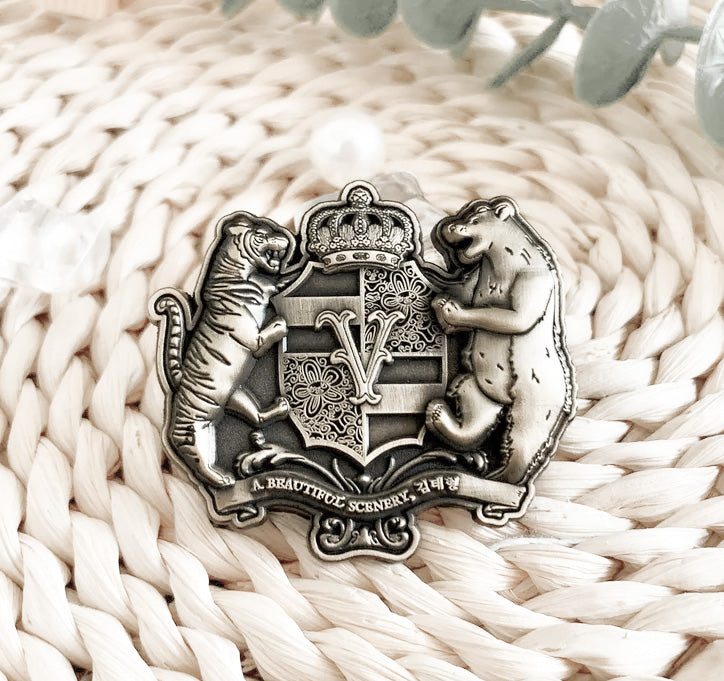 A Beautiful Scenery enamel pin resting on woven straw